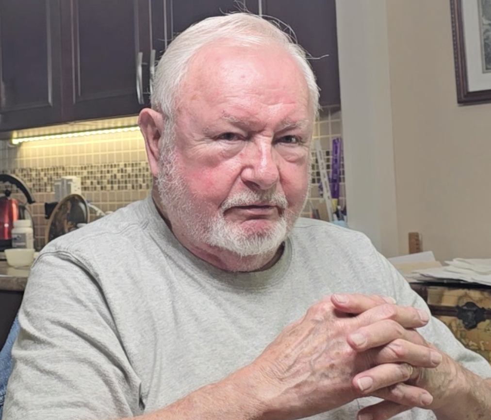 Photograph of United States Army veteran George Cochran. Sitting for an interview with his hands together in front of him.