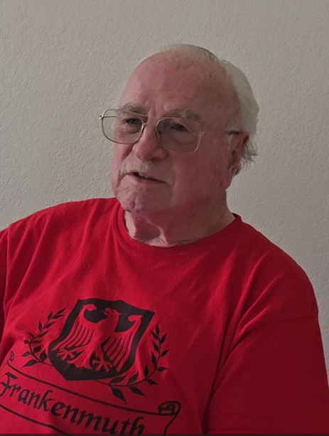 Image of Robert Akins, a United States Army veteran. Answering questions for an interview, wearing a orange shirt.